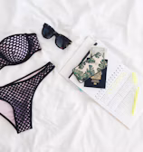 Fashionable flat lay of travel essentials on a sandy beach.
