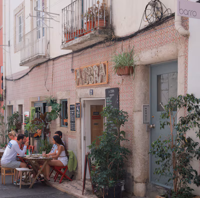 Giovana enjoying a chic outdoor café with tropical plants.
